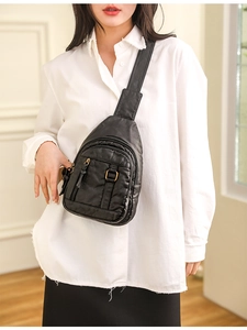 Close-up of black washed leather chest bag showing soft texture and metal zipper details