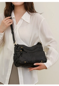 Détail d'un sac bandoulière en similicuir noir lavé avec plusieurs poches zippées et rivets