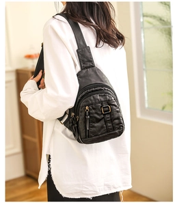 Close-up of black washed leather crossbody bag showing multiple pockets and bronze zippers