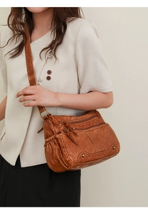 Detail einer Vintage braunen Leder-Umhängetasche mit Reißverschlüssen und Nieten am Modell