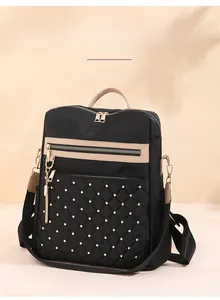 Detail of quilted black nylon backpack with gold studs, beige handles and tassel zipper