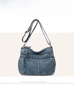 Frontansicht der Jeansblauen Vintage-Umhängetasche aus Leder mit Reißverschlüssen und Nieten