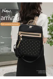 Detail of black quilted nylon backpack with gold studs and removable tassel charm
