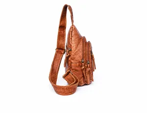 Side view of brown washed leather chest bag with multiple zipper pockets and adjustable strap