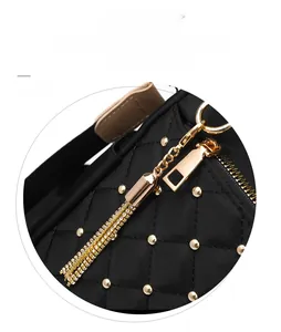 Close-up of black quilted nylon backpack with gold studs and tassel zipper detail
