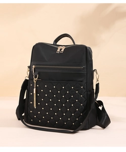 Close-up of black quilted nylon backpack featuring gold studs and smooth zipper detail