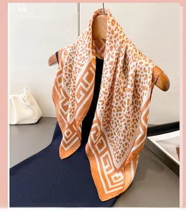 Detail of leopard print silk scarf with interlocking patterns hanging on a wooden hanger