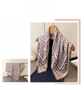 Detail view of leopard print silk scarf featuring brown geometric patterns and satin texture
