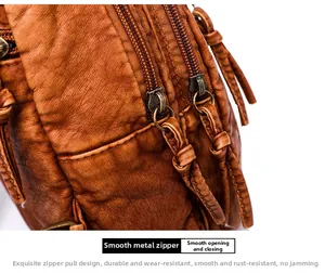 Close-up of vintage brown washed leather bag featuring dual smooth metal zippers