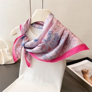 Detailansicht eines Seidenschals mit rosa und blauen Blumenmustern an einer Schaufensterpuppe