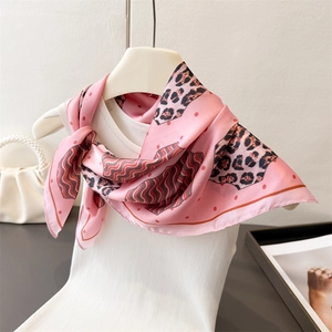Detail of pink silk-like scarf with leopard print and wavy stripes styled on a vest