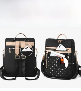 Detail view of a black quilted nylon backpack with multiple zippered pockets and gold studs