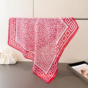 Leopard print silk scarf in red and white with geometric borders hung on a stand