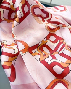 Detailed close-up of pink silk scarf featuring geometric B patterns and floral outlines