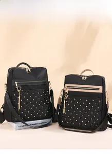 Detail of two black quilted backpacks with gold studs and tassel zippers on books