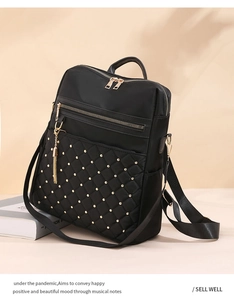 Close-up of black quilted backpack featuring golden rivets, metal zipper, and tassel detail