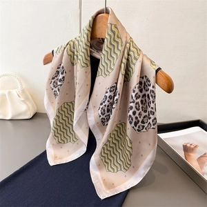 Elegant leopard print silk scarf with yellow wavy patterns on a wooden hanger