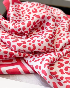 Close-up of red leopard print silk scarf showing soft satin texture and detailed hem