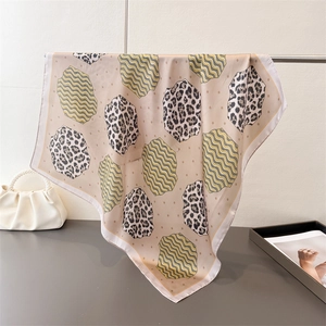 Close-up of lightweight leopard print silk scarf draped elegantly on a metal stand