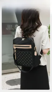 Detail of black nylon backpack featuring quilted diamond pattern and gold stud accents