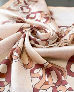 Macro shot of silk scarf showing glossy texture with abstract geometric lines and rose print