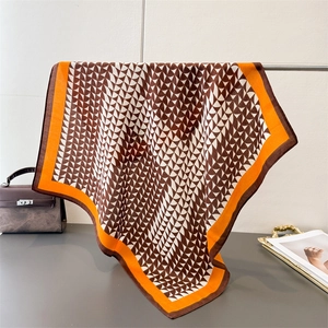 Close-up of silk-textured square scarf featuring geometric patterns and orange borders