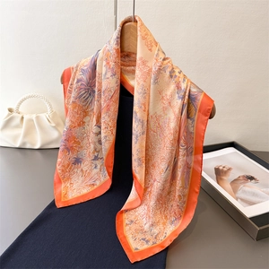 Eleganter orangefarbener Seidenschal mit Blumenmuster auf schwarzem Kleid und Holzbügel