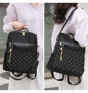 Detailed view of black quilted backpack with gold studs and tassel in multiple carry modes