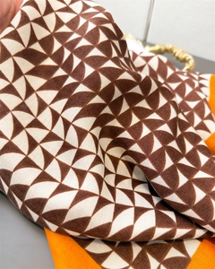 Detailed macro view of geometric pattern scarf with soft satin texture and orange border