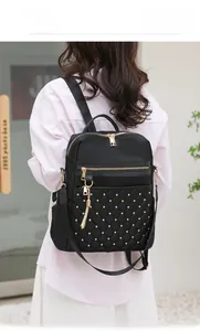 Detailed view of quilted black nylon backpack featuring gold studs and tassel charm