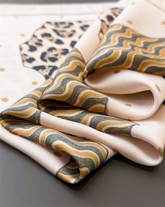 Detailed close-up showing leopard print and golden dot patterns on silk scarf fabric