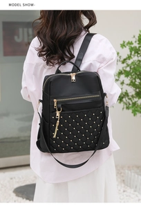 Outdoor model shot of a black quilted backpack with gold studs and side pocket detail