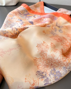 Nahaufnahme des bedruckten Seidenschals mit hochwertiger Textur und orangem Randdetail