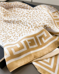Macro detail of leopard print satin scarf with Greek key border on elegant dark tray