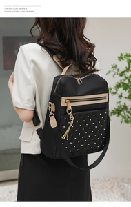 Quilted black nylon backpack with gold studs and tassel detail on female model