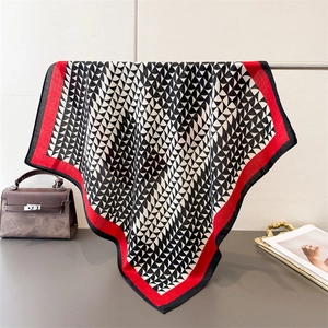 Detail of square scarf with black and white fan pattern and red border in a luxury setting