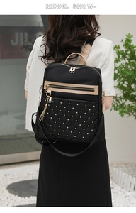 Detail of black nylon quilted backpack with gold rivets and tassel on model back