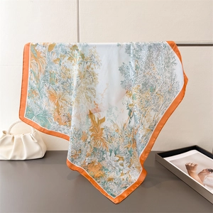 Detailansicht eines Seidenschals mit Blumenmuster und orangefarbenem Saum an Stange