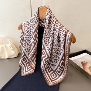 Fashionable leopard print silk scarf with geometric border hanging on a wooden hanger