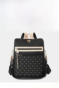 Detail view of black quilted backpack featuring gold rivets and elegant tassel zip puller