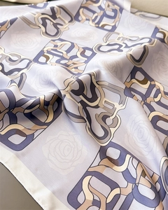 Macro detail of high-quality satin scarf featuring floral and geometric chain patterns
