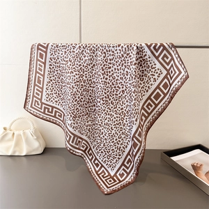 Detail of leopard print silk scarf with geometric border hanging on a metal rack