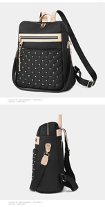 Detail of quilted black backpack featuring gold rivets and elegant beige handles