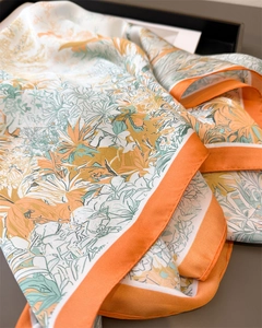 Detailansicht des Seidenschals mit tropischem Blumendruck und orangefarbenem Saum