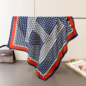 Detail of navy geometric pattern scarf with vibrant orange edges and silky texture
