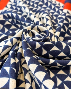 Detailed view of blue and white herringbone scarf with vibrant red borders and twill texture