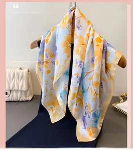 Detailed view of floral silk scarf hanging on a wooden hanger with fashion accessories