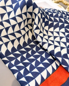 Detail of navy geometric cotton linen scarf with orange herringbone border and knit texture