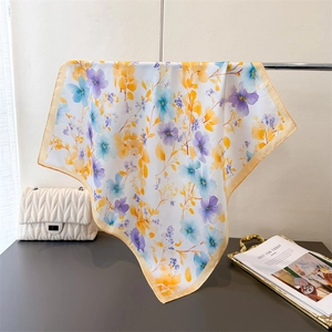 Detail of floral silk-like square scarf draped elegantly with a matching quilted handbag