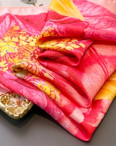 Close-up of floral silk scarf with vibrant red and yellow blooms and glossy texture